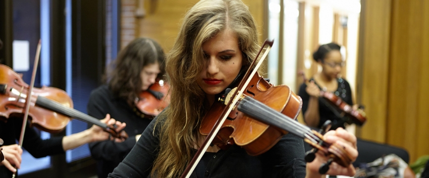 Young woman playing violin in the green room