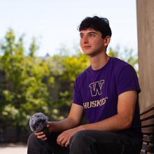 Leo Freedman sitting on a bench on campus, with a microphone in his hand.